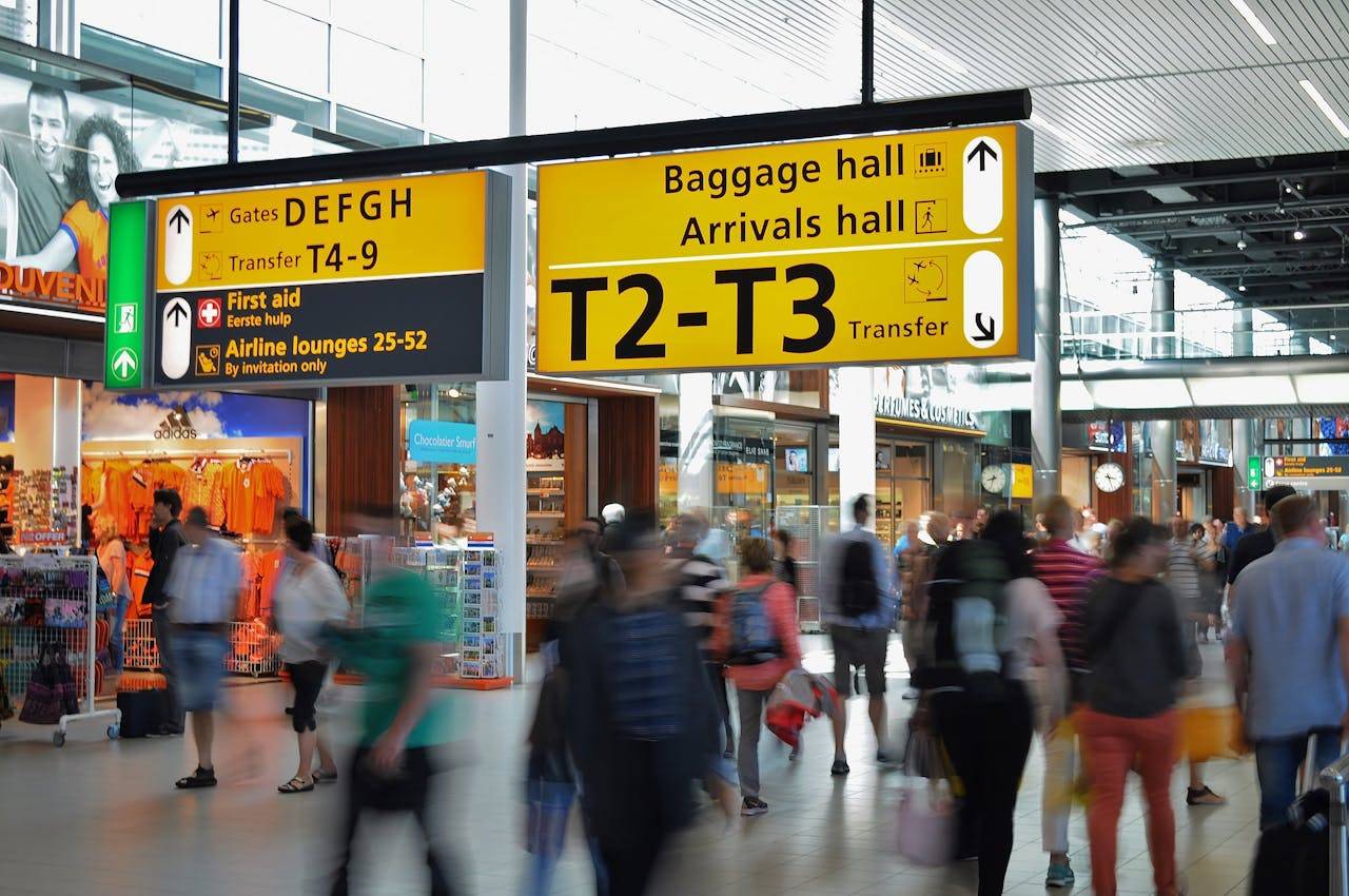 Crowded airport with motion blur and clear signage indicating baggage and arrival halls.