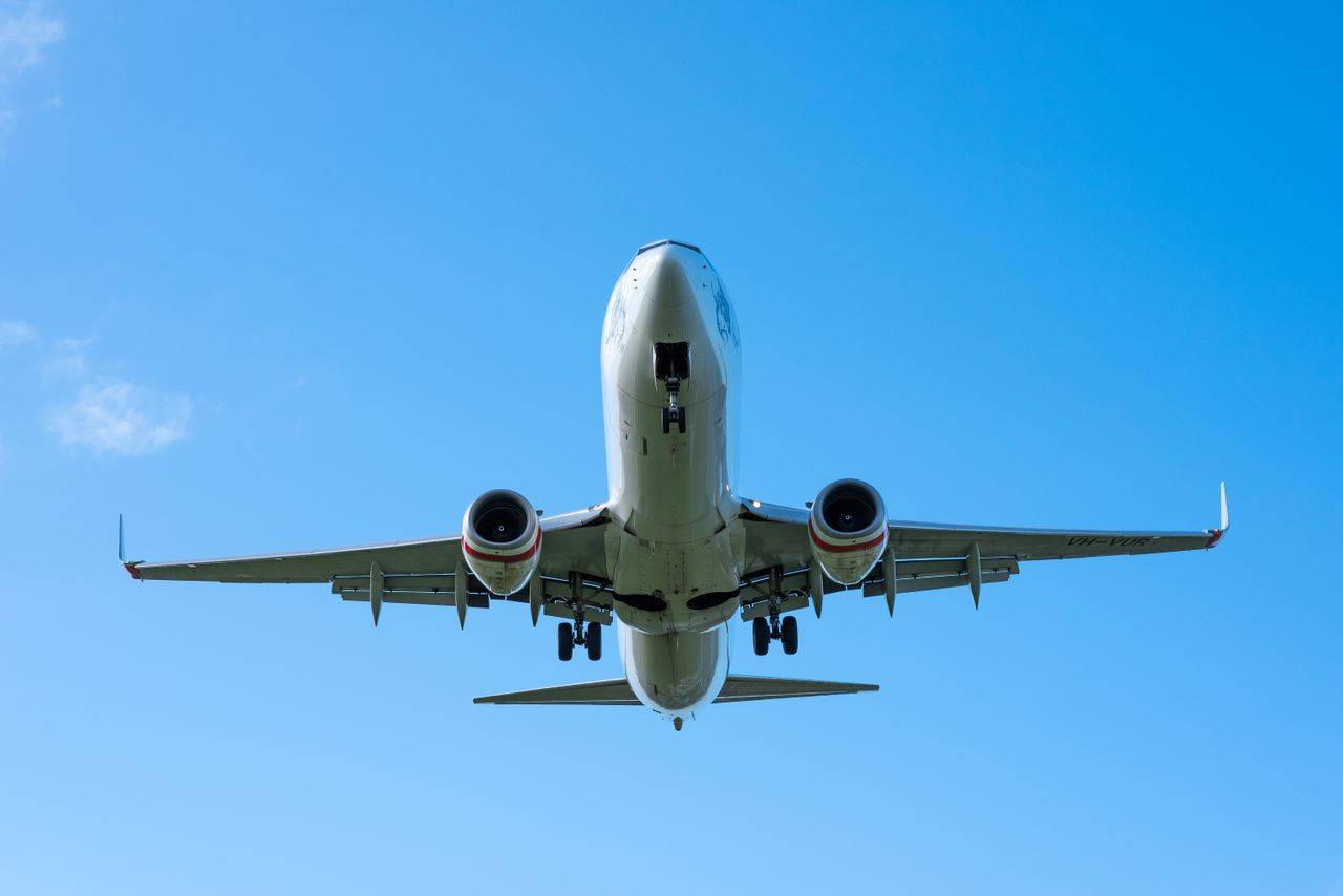 A low-angle shot of a Boeing airplane taking off, set against a clear, vivid blue sky.