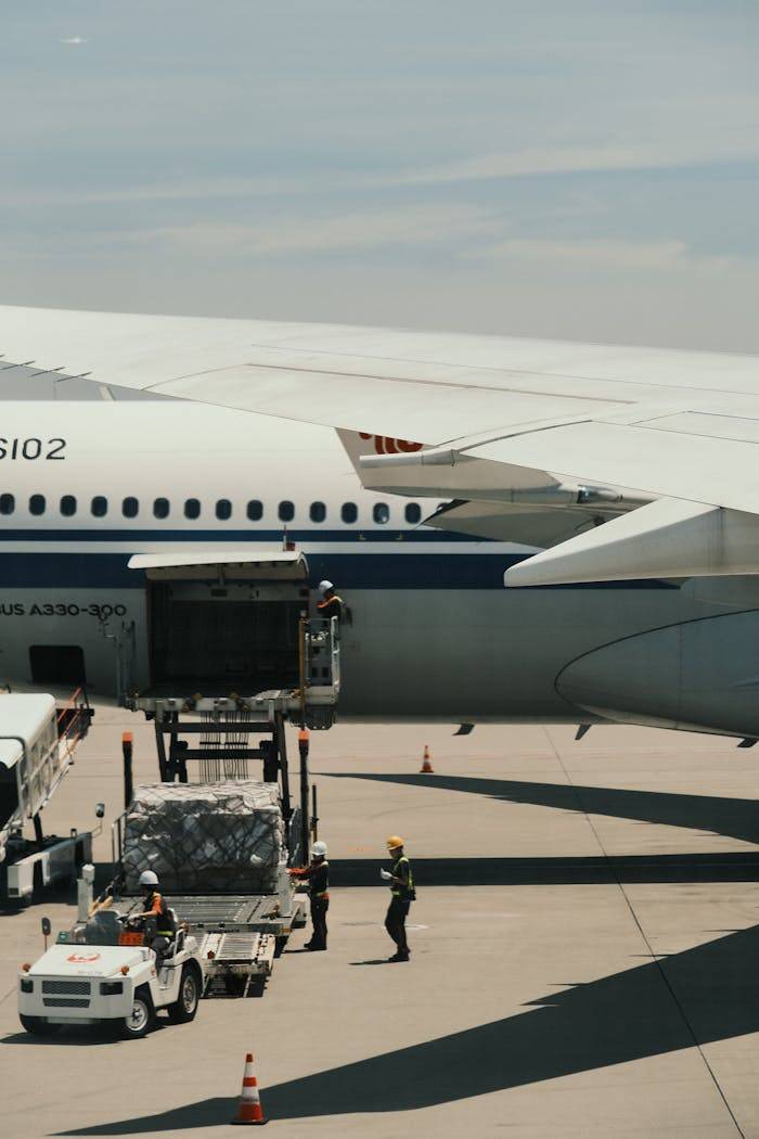 Airbus A330 being loaded with cargo on an airport runway, showcasing transportation logistics.