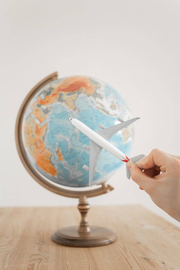 services-02 Close-up of a hand with a toy airplane in front of a globe, symbolizing travel and exploration.